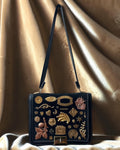 1960s black suede Gathered Charm Bag adorned with antique brass charms and collected details.